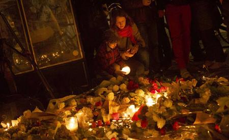 銃撃されたパリの飲食店前でキャンドルをともして追悼する親子＝１４日（ＡＰ）