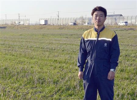 国道沿いの小麦畑に立つ岡野貴儀さん＝４日、北海道当別町