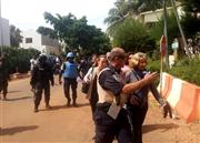 ２０日、西アフリカ・マリの首都バマコのホテルで人質となった後、解放されて治安部隊にエスコートされる人々（ゲッティ＝共同）