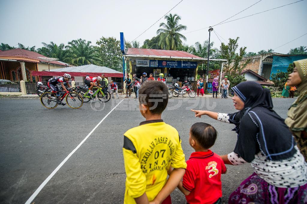 中間スプリントラインで観戦する地元の人たち。自転車ロードレースは生活道路がレースコースとなり、誰もが無料で観戦できるスポーツ＝２０１５年１０月初旬、インドネシア・西スマトラ州（田中苑子さん撮影）