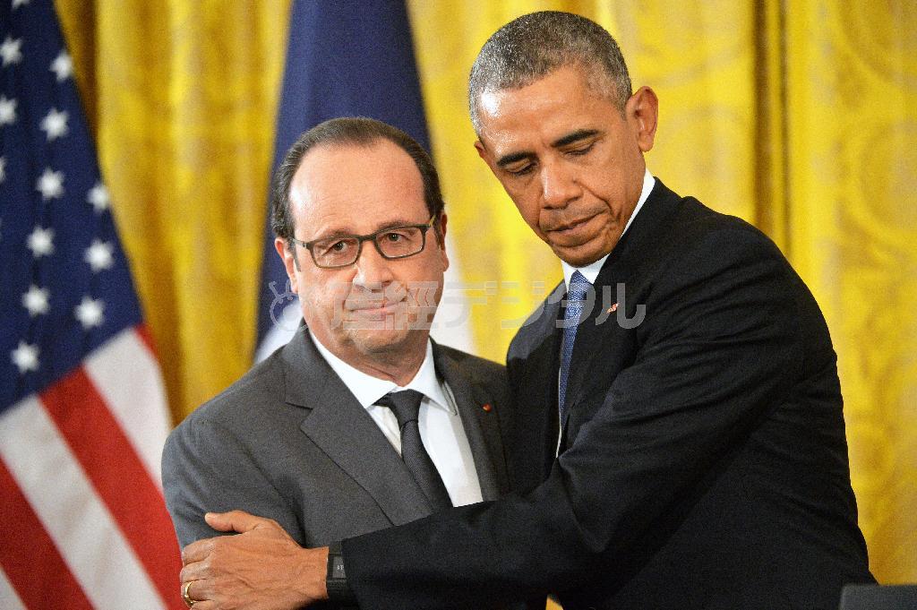 １１月２４日、ホワイトハウスでの記者会見で、フランスのフランソワ・オランド大統領（左）を抱きしめるバラク・オバマ米大統領。両首脳は「イスラム国」への空爆拡大で合意したが、会談をリードしたのはオランド氏で、オバマ氏はどこまでも受け身だった＝２０１５年、米国・首都ワシントン（ＵＰＩ＝共同）