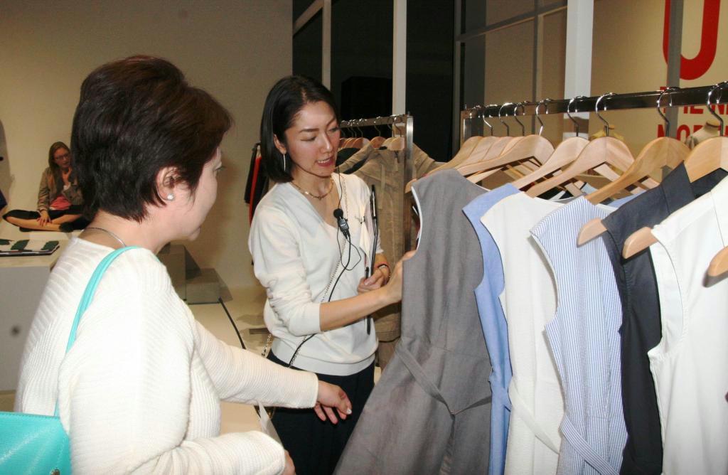 スタッフから春夏の新作の特徴などの説明を受ける来場者（左）＝１日、東京都渋谷区