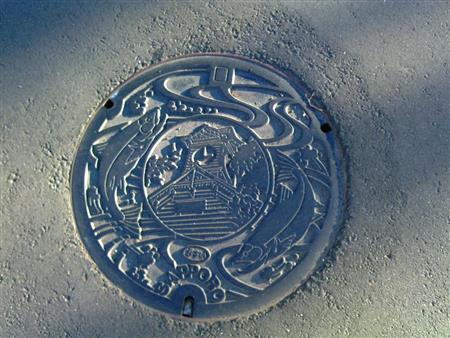 時計台と鮭があしらわれた札幌ご当地デザインのマンホール。ついに２０センチほど積雪したので、見えなくなってしまいました＝２０１５年９月１６日、北海道札幌市（乾ルカさん撮影）