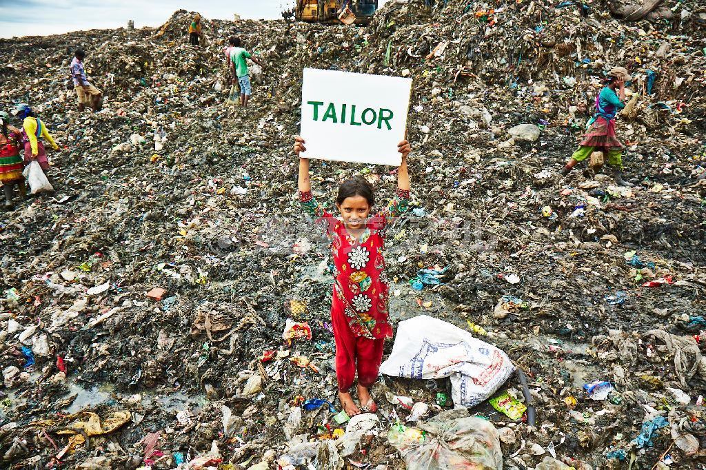 売れるものを探しに行くゴミ山で、将来の夢を書いたカードを掲げてくれたモスミ（中央）＝２０１５年７月２９日、バングラデシュ・首都ダッカ（ワールド・ビジョン・ジャパン撮影）