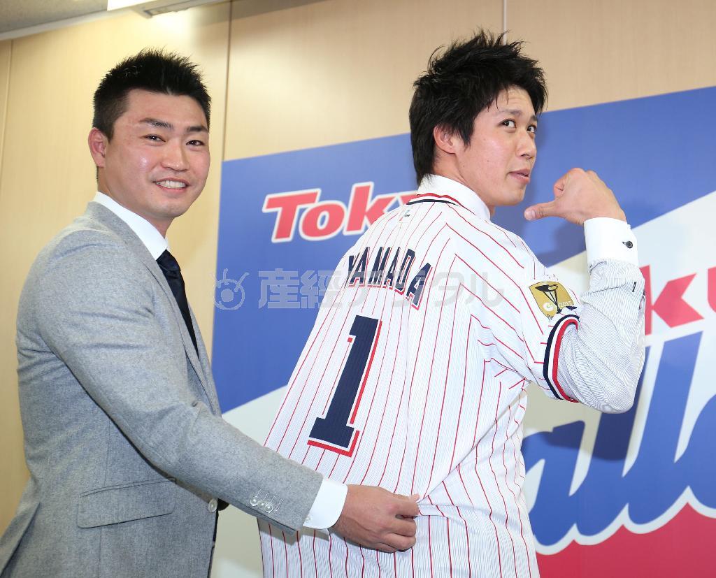 マリナーズの青木宣親（のりちか）外野手（左）からユニホームを手渡されるヤクルト・山田哲人（てつと）＝２０１５年１２月８日、東京都港区（大橋純人撮影）