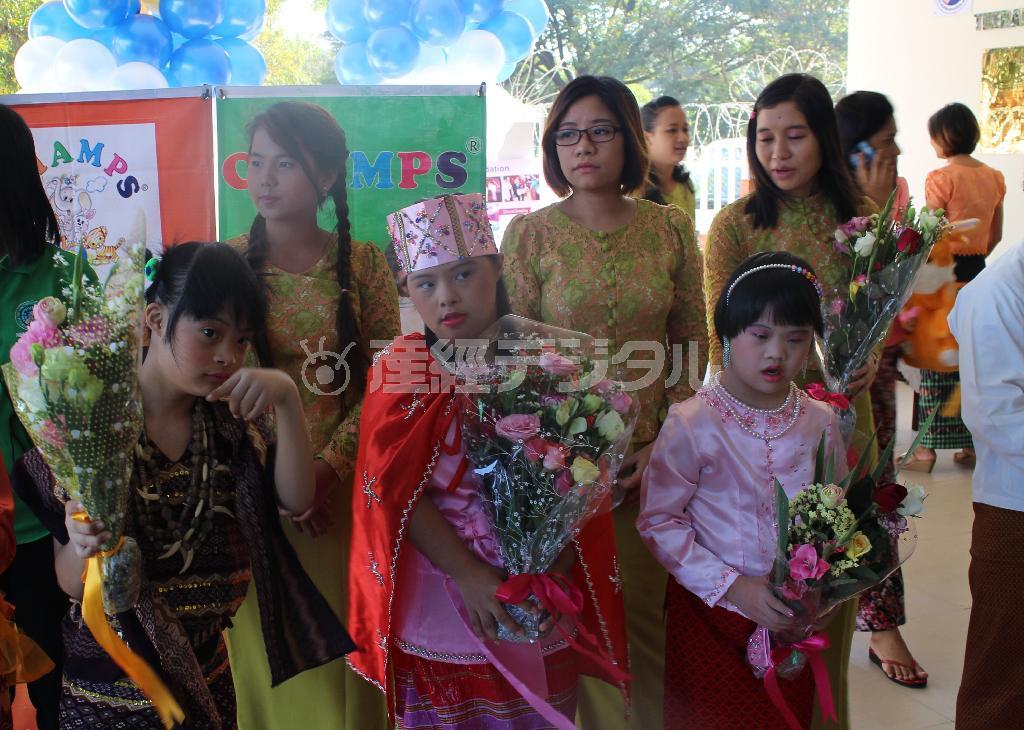 療育センターの新しいビルの竣工式で、各地域の民族衣装を着て出席者を出迎える子供たち。トレーナー（後列）は子供たちをマンツーマンでサポートしている＝２０１４年１１月２２日、ミャンマー・ヤンゴン（日本財団撮影）