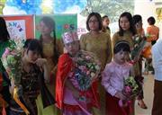 療育センターの新しいビルの竣工式で、各地域の民族衣装を着て出席者を出迎える子供たち。トレーナー（後列）は子供たちをマンツーマンでサポートしている＝２０１４年１１月２２日、ミャンマー・ヤンゴン（日本財団撮影）