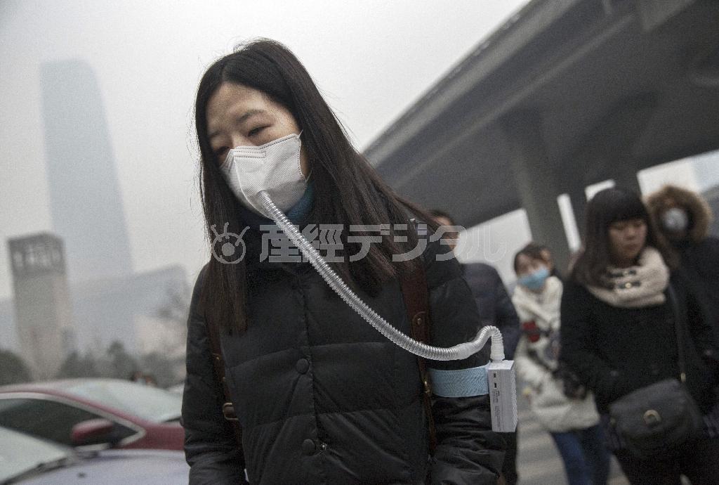 深刻な大気汚染が続く首都北京市で、空気吸入器付きのマスクをつけて歩く女性。中国では空気も“爆買い”の対象品のようだ＝２０１５年１２月１９日（ゲッティ＝共同）