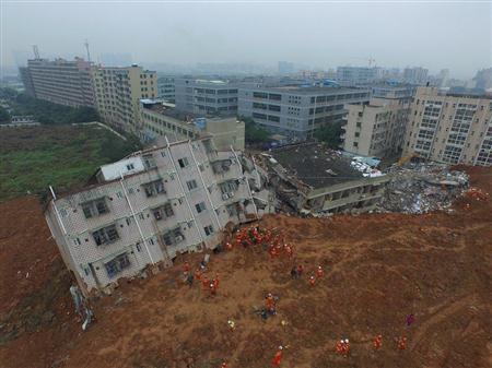 中国・広東省深セン市の工業団地で、土砂崩れにより倒壊した建物を捜索する救助隊員ら＝２０１５年１２月２１日（ロイター）