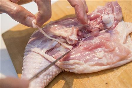 骨の両脇に包丁を入れ、切り開きながら脂の筋を見つけて取り除く(松下二郎さん撮影、提供写真)