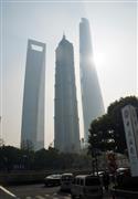 中国で最も高い地上１２８階建ての超高層ビルとして建設中の「上海中心大厦」（６３２メートル、右）。この日は正午段階でＰＭ２．５を含む大気指数が３２３と、重度の大気汚染で超高層ビルもかすんでいた＝２５日、上海（河崎真澄撮影）