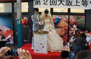 ケーキの代わりにお好み焼にコテを入れて「ケーキ入刀」する新郎新婦＝５日午後、大阪市城東区
