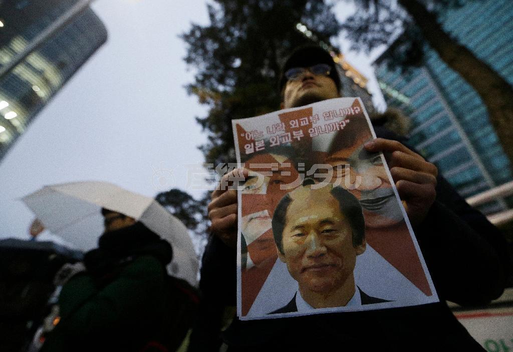 １２月３０日、韓国・首都ソウルの日本大使館前で、韓国の朴槿恵（パク・クネ）大統領とちょんまげ姿に合成した尹炳世（ユン・ビョンセ）外相、安倍晋三（しんぞう）首相を組み合わせたコラージュ写真を掲げ、慰安婦問題をめぐる日韓合意に抗議する人＝２０１５年（ＡＰ）