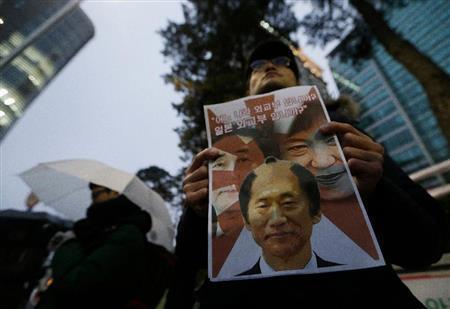 １２月３０日、韓国・首都ソウルの日本大使館前で、韓国の朴槿恵（パク・クネ）大統領とちょんまげ姿に合成した尹炳世（ユン・ビョンセ）外相、安倍晋三（しんぞう）首相を組み合わせたコラージュ写真を掲げ、慰安婦問題をめぐる日韓合意に抗議する人＝２０１５年（ＡＰ）