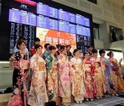 東京証券取引所で行われた大発会で、株価ボードの前に並んで記念撮影をする晴れ着姿の女性たち＝２０１６年１月４日、東京都中央区（早坂洋祐撮影）