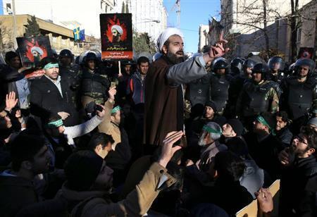 イランの首都テヘランにあるサウジアラビア大使館前で、処刑されたシーア派指導者ニムル師のポスターを掲げて抗議する人々＝２０１６年１月３日（ＡＰ）