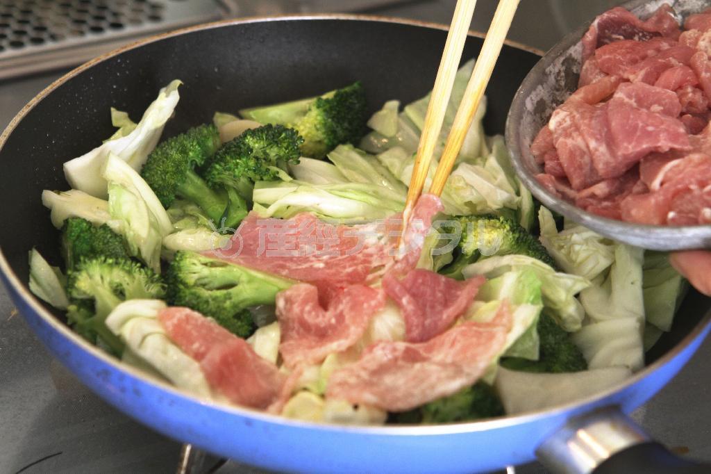 豚肉とブロッコリーのフライパン蒸し（作り方２）＿＿フライパンに油を熱し、キャベツ、ブロッコリー、ニンニクをさっと炒め、水を入れてならして一度火を止める。［作り方１：調理した豚肉］を広げて野菜の上に均一にのせる。