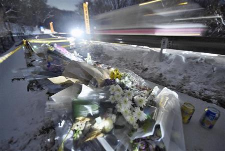 行き交う車両のヘッドライトに照らされる、バス転落事故の現場に供えられた花束＝２０１６年１月２１日夜、長野県北佐久郡軽井沢町（共同）