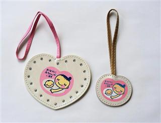 昨年１２月に発売された「初めてのたまごクラブ」の付録のマタニティーマークをあしらったストラップ（右）。平成２３年の付録（左）に比べ小さくなっている（ベネッセコーポレーション提供）