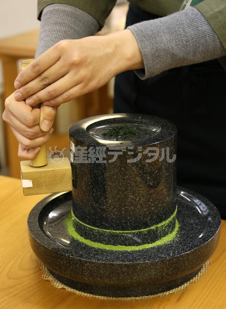 石臼での抹茶づくり体験。持ち手をしっかり握り約２０分かけてゆっくりとひく。石臼の重さは約２０キロあるという＝２０１５年１２月１８日、京都府宇治市（志儀駒貴撮影）