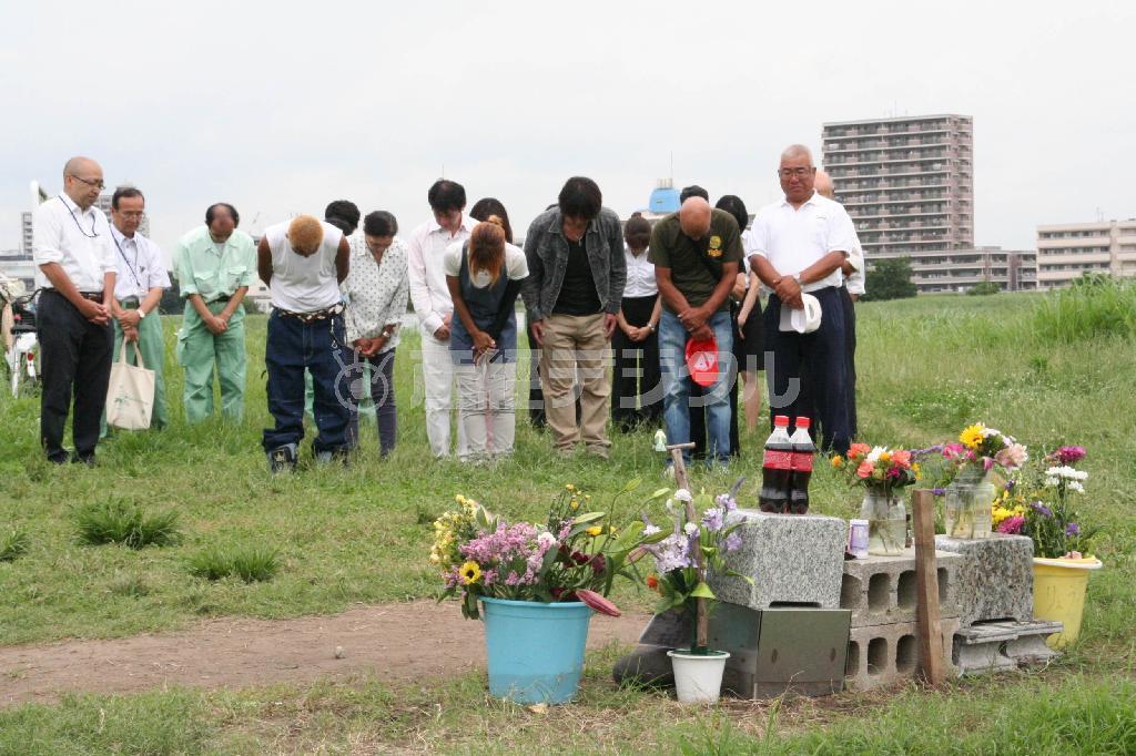 花の撤去を前に黙祷（もくとう）するボランティアら＝２０１５年６月３０日、神奈川県川崎市川崎区（那須慎一撮影）