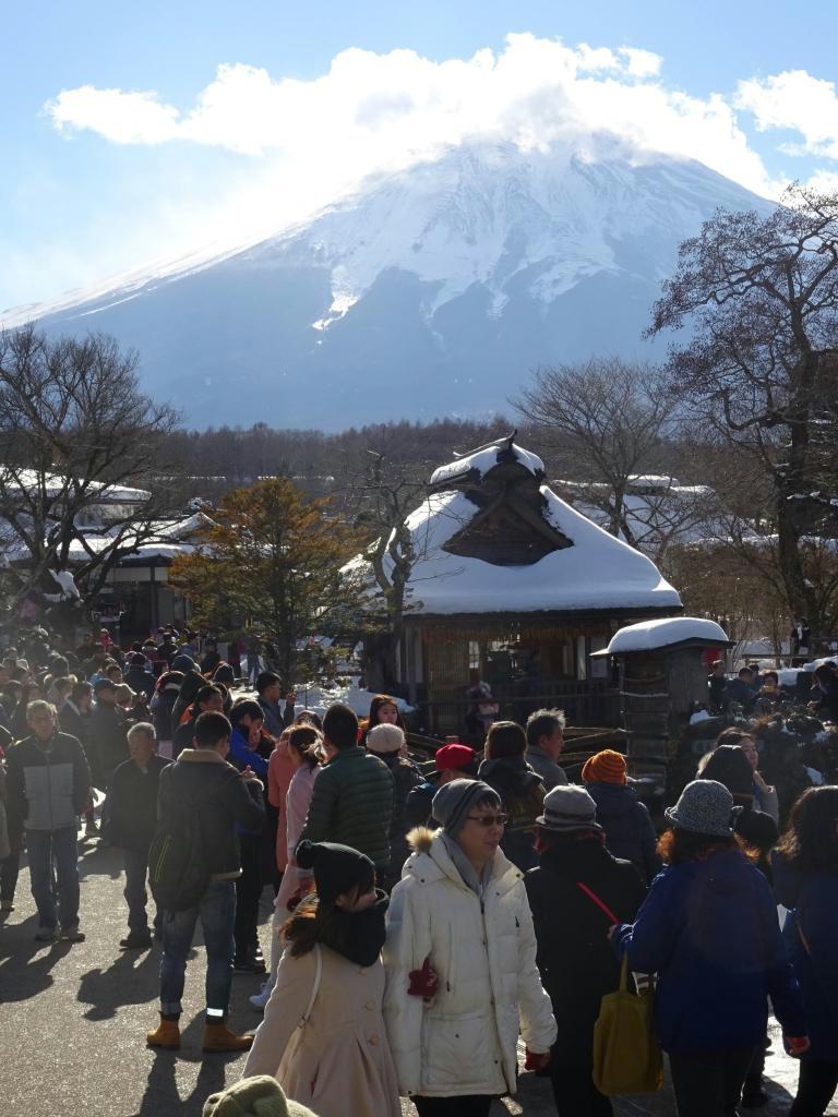 富士山麓の名所「忍野八海」を見物する中国人ツアー客。国内観光客が少ない季節にも大挙訪れる＝山梨県忍野村
