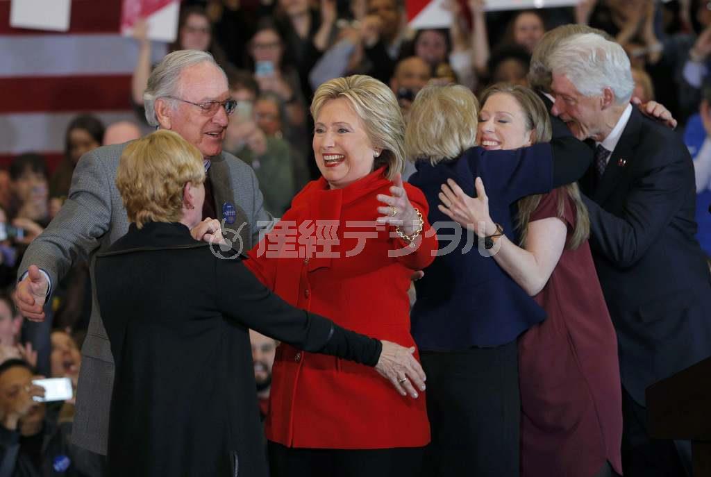 トム・ハーキン元米国上院議員（左）らと抱き合うヒラリー・クリントン氏。予想外の苦戦を強いられた＝２０１６年２月２日、米アイオワ州デイモン市（ロイター）