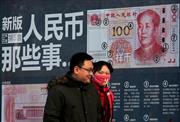 新しい百元札のＰＲデザインが描かれた壁の前を歩くカップル。市場では人民元の切り下げ観測が高まっている＝北京市内（ＡＰ）