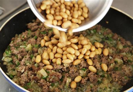チリコンカン＿カレー風味（作り方２）＿＿フライパンにオリーブ油を熱し、タマネギをよく炒め、ピーマンを加えてさっと炒める。［作り方１：調理した豚ひき肉］を加えてポロポロになるまで炒め、さらに大豆を加えてさっと炒める。