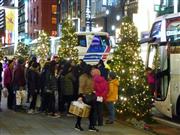 東京・銀座で買い物する中国人観光客らと路上駐車するバス＝１月