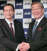 アサヒグループホールディングスの泉谷直木社長（右）と握手する小路明善新社長＝９日、東京都千代田区