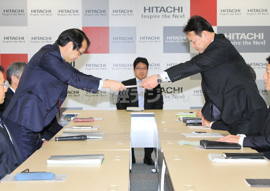 日立製作所の担当役員、中畑英信常務（左）に要求書を手渡す日立労組の坂本達哉委員長＝２０１６年２月１８日、東京都千代田区（荻窪佳撮影）