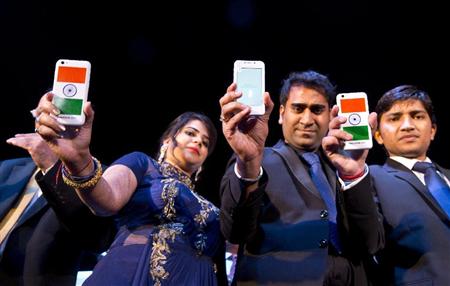 １７日、インドの首都ニューデリーで２５１ルピー（約４２０円）のスマートフォンを披露する地場メーカーの関係者（ＡＰ）