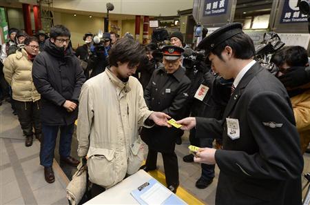 北海道新幹線開業日の一番列車の切符を求め、ＪＲ函館駅で駅員から整理券を受け取る人たち＝２６日午前５時