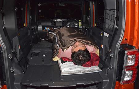 寝袋に収まる杉渕。写真のように、下半身をクルマの真ん中よりしてに寝ると、シートの段差を感じにくいそうだ。そうなると、大人２人が並んで寝るスペースはない