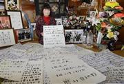 東日本大震災の津波で行方不明になった夫を思って記したメッセージと熊谷幸子さん。仏壇の周りには、死亡届を出していない夫の写真が並ぶ＝２０１５年１２月１７日、岩手県陸前高田市（共同）