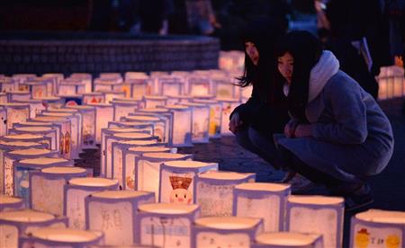 ≪宮城≫宮城県の名取市役所前に置かれた絵灯籠を見つめる人たち。東北福祉大学２年生の菅原万莉さん（左）と薄井優美さはボランティア活動を行っているという＝１１日午後（納冨康撮影）