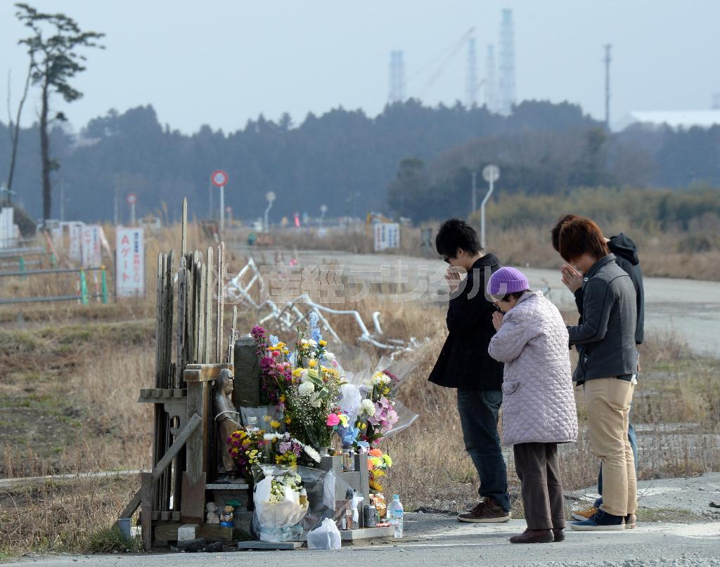 原発事故で全町避難が続く福島県双葉郡浪江町請戸地区で、地震発生時刻の午後２時４６分に慰霊碑前で手を合わせる人たち＝２０１６年３月１１日午後（鴨川一也撮影）