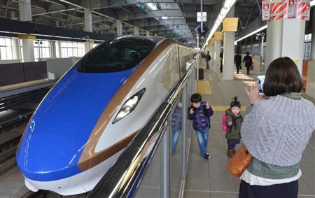 北陸新幹線の車両前で記念撮影する人たち＝２月２７日、ＪＲ金沢駅