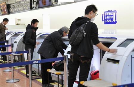 羽田空港に設置された自動で手荷物を預け入れられる機械を利用する乗客ら