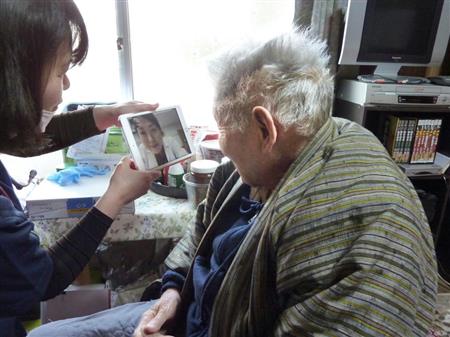 訪問看護師（左）が持ってきたタブレット端末のテレビ電話で主治医と話す藤沢昭さん＝１日、高松市内