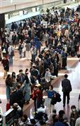 全日空のシステム障害で、羽田空港第２ターミナルの国内線カウンタ－に長い列を作る乗客＝３月２２日午前、東京・羽田空港（早坂洋祐撮影）