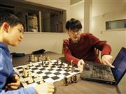 パソコンを使ってチェスの指導をする小島慎也さん（右）＝２月、東京都渋谷区