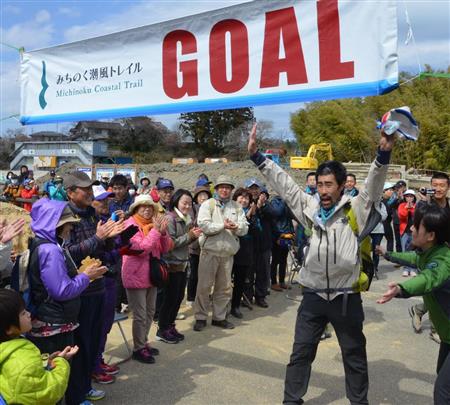 みちのく潮風トレイルを踏破し、住民らに拍手で迎えられるタレントのなすびさん（手前右から２人目）＝２７日午後、福島県相馬市
