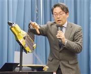 エックス線天文衛星「ひとみ」の模型を使って記者会見するＪＡＸＡの担当者＝１日午後、東京都千代田区