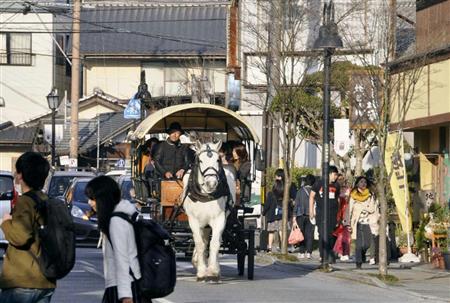 観光客に人気の周遊用の馬車が走るＪＲ由布院駅前の街並み。地方にも外国人観光客の姿が増えている＝大分県由布市