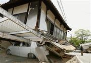 強い地震で押しつぶされた家屋と自動車＝１５日午前１０時３１分、熊本県益城町