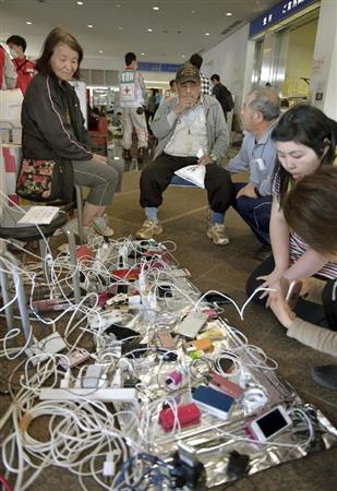 避難所となった体育館で携帯電話の充電をする人たち＝１７日午前１１時２５分、熊本県益城町