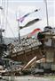 地震で倒壊した住宅の脇にたなびくこいのぼり＝１７日午前１１時、熊本県益城町