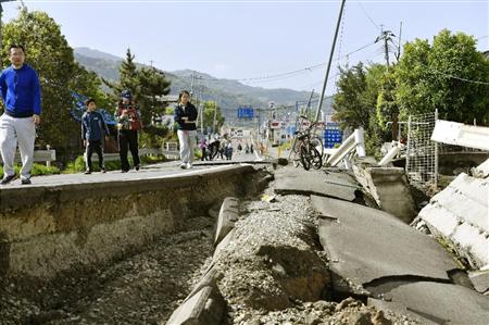 地震で亀裂が入った道路を歩く人たち＝１７日午前９時１４分、熊本県益城町